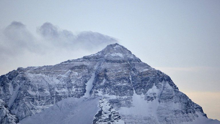 Wind blows snow off the summit at dusk of the world's highest mountain Mount Everest, also known as Qomolangma, in the Tibet Autonomous Region